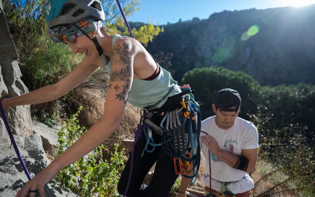 Smiling professional woman with curly hair wearing a necklace and gray cardigan in a bright office setting